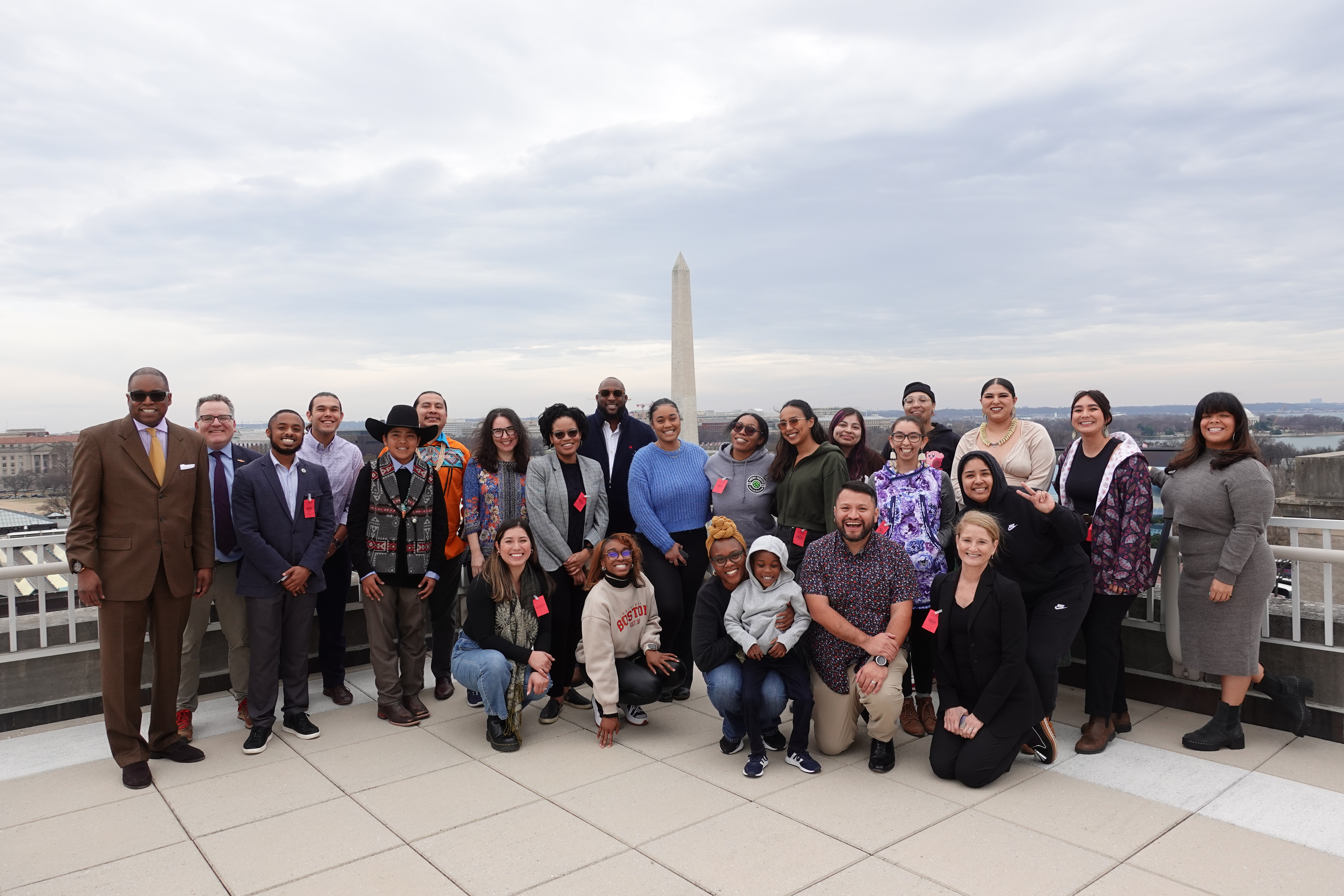 A big group poses in front of the DC skyline with the Washington Monument in the background